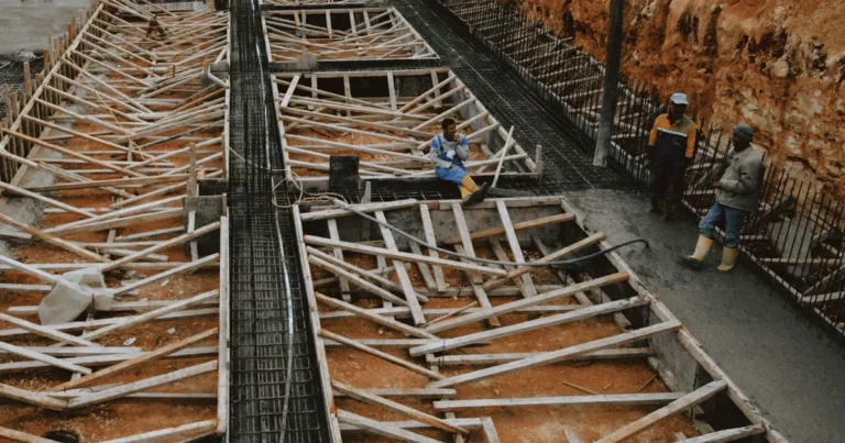 Nakładanie czarnej masy bitumicznej na ścianę fundamentową w wykopie