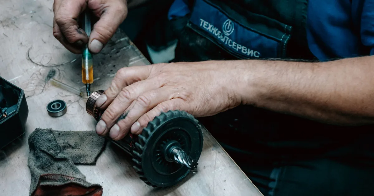 Technik pracuje precyzyjnymi narzędziami przy kole zębatym na warsztatowym blacie