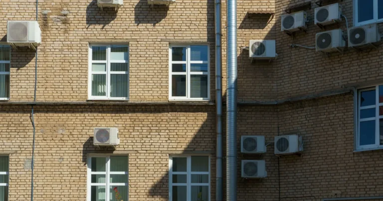Jednostka zewnętrzna po montażu klimatyzacji, zamocowana na konsolach na ścianie bloku mieszkalnego