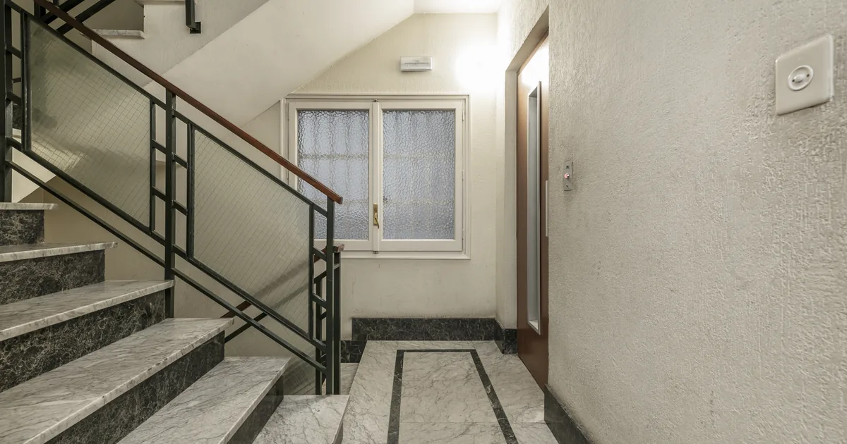 Schody na klatce schodowej bloku mieszkalnego z lat 70. z metalową balustradą
