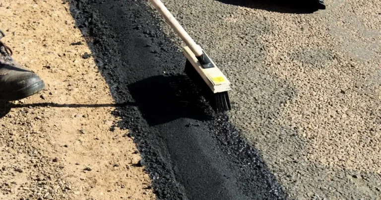 Naprawa nawierzchni asfaltowej, ciemna masa bitumiczna i narzędzia drogowca