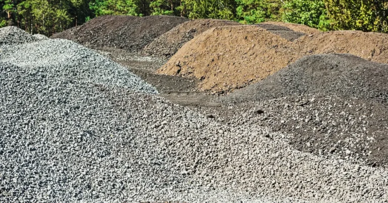 Pryzmy kruszywa, tłucznia i ziemi na placu budowy - materiały do utwardzania terenu pod dojazd